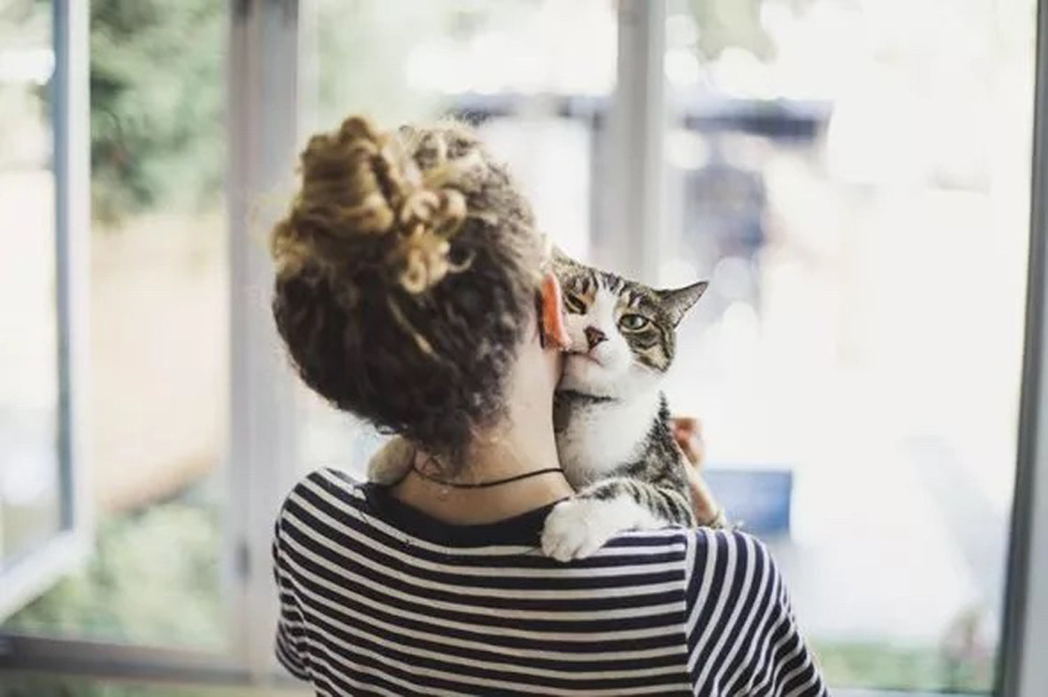 women looking out the window with pet cat
